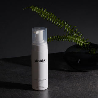 Medik8 Gentle Cleanse flaske på mørk baggrund med bregne