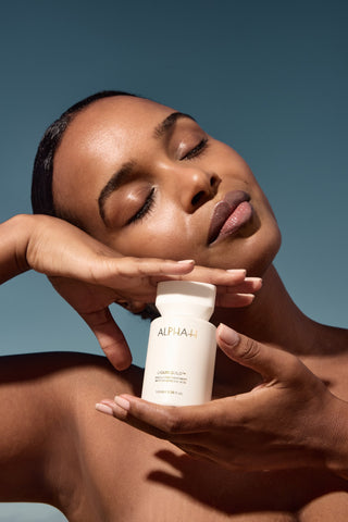 Alpha-H Liquid Gold Exfoliating Treatment model med flaske i sollys